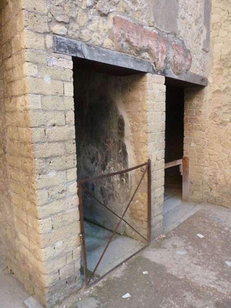 Ins. V 7, Herculaneum, September 2015. Two doorways in south-east corner of atrium.
The central one leads towards the internal courtyard (no access) and the other, on the right, leads into the triclinium.